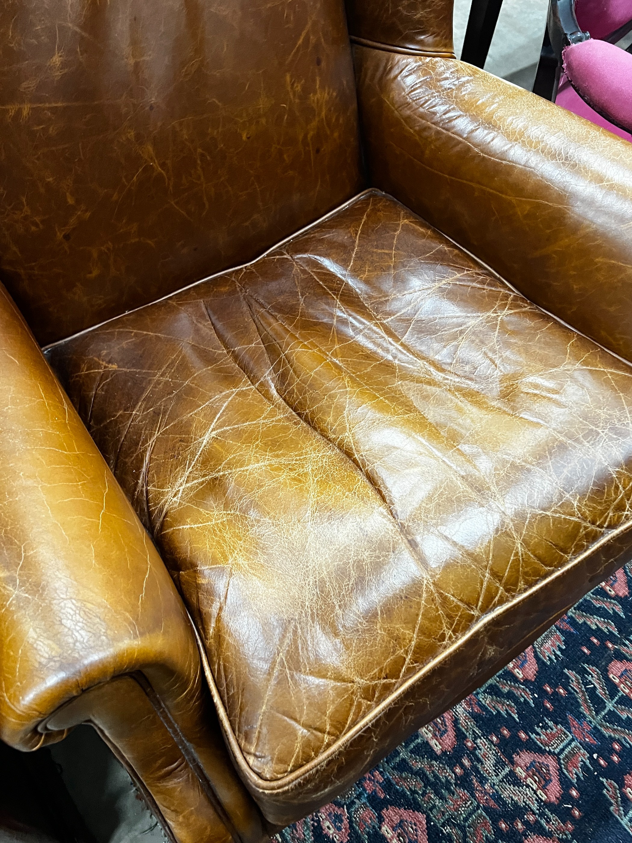 A Victorian style tan leather upholstered wingback armchair, width 78cm, depth 84cm, height 100cm